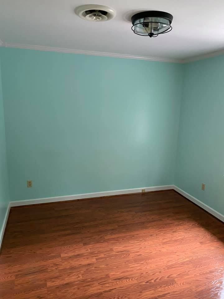 An empty room with light blue walls and hardwood floors.
