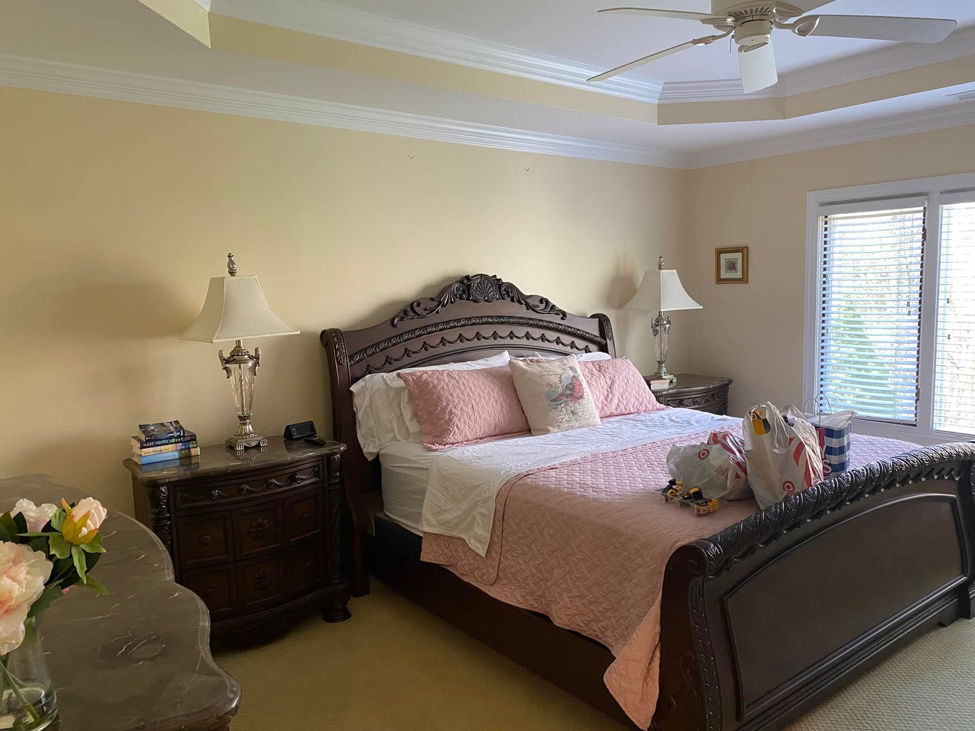 A bedroom with a king size bed , nightstand , lamps and a ceiling fan.