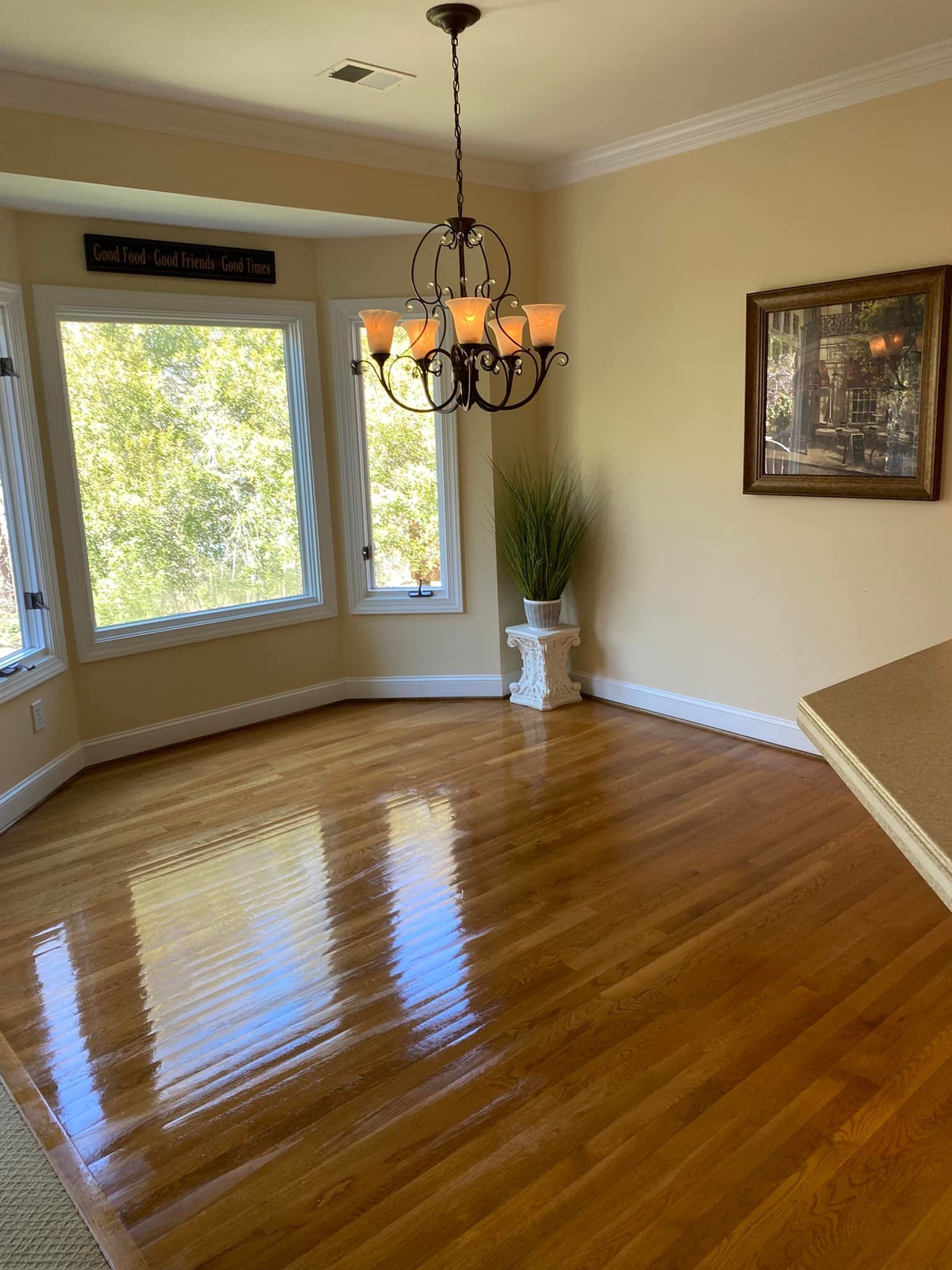 An empty dining room with hardwood floors and a chandelier hanging from the ceiling.