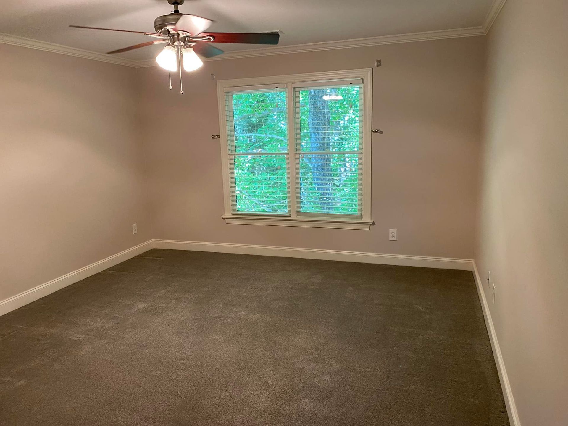 An empty bedroom with a ceiling fan and a window.