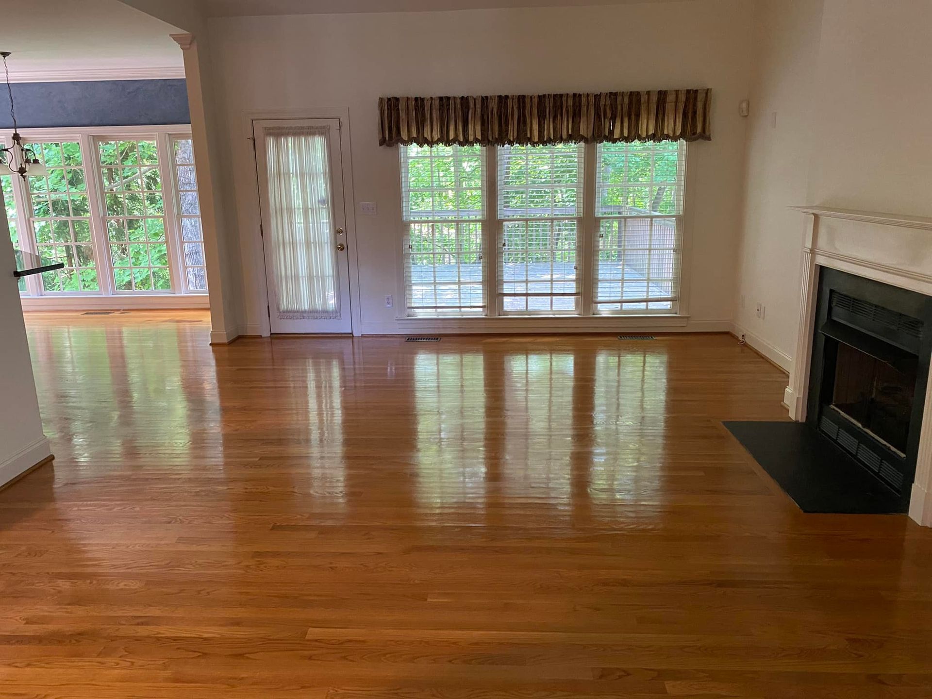 An empty living room with hardwood floors and a fireplace.