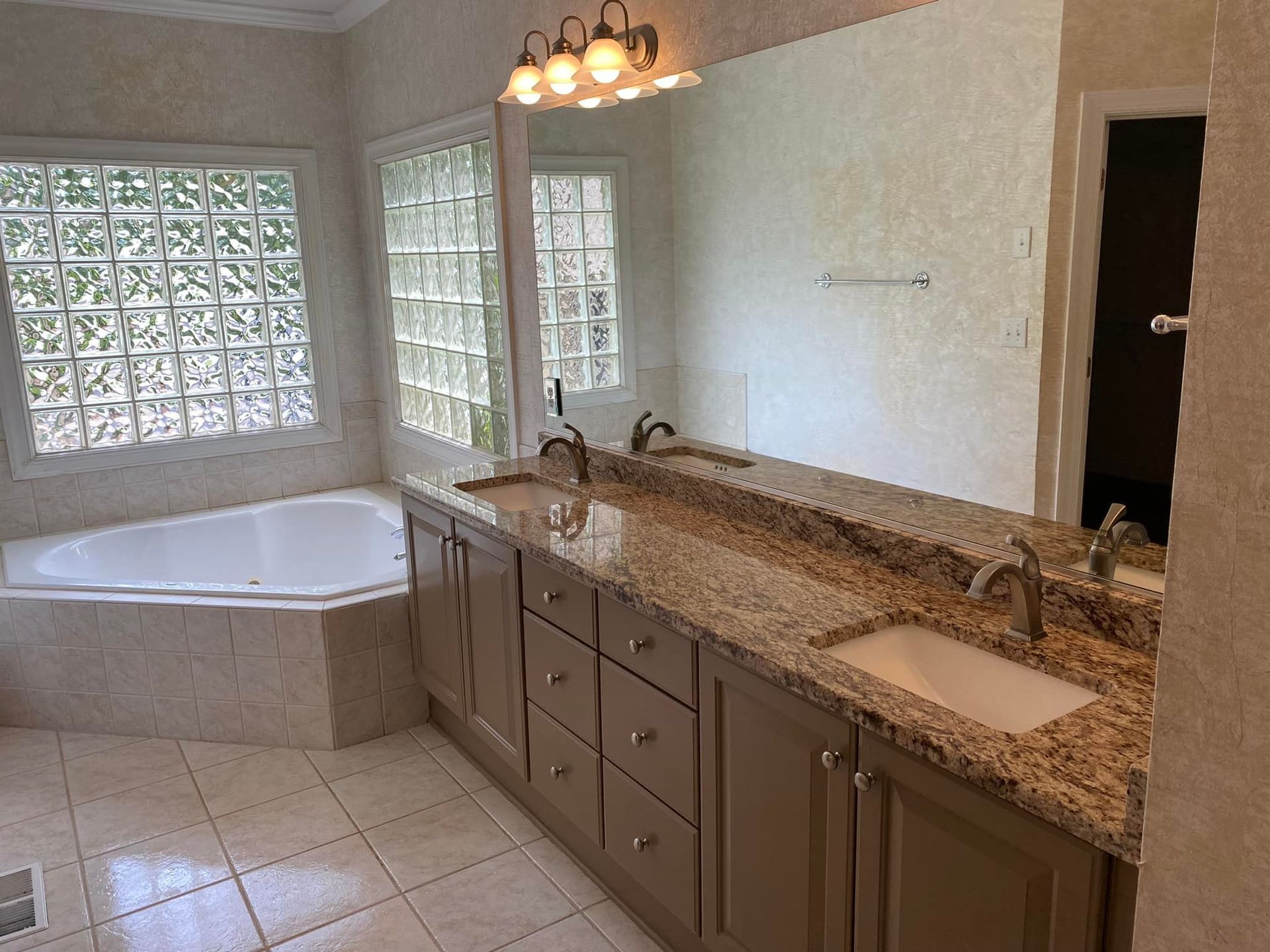 A bathroom with two sinks , a tub and a large mirror.