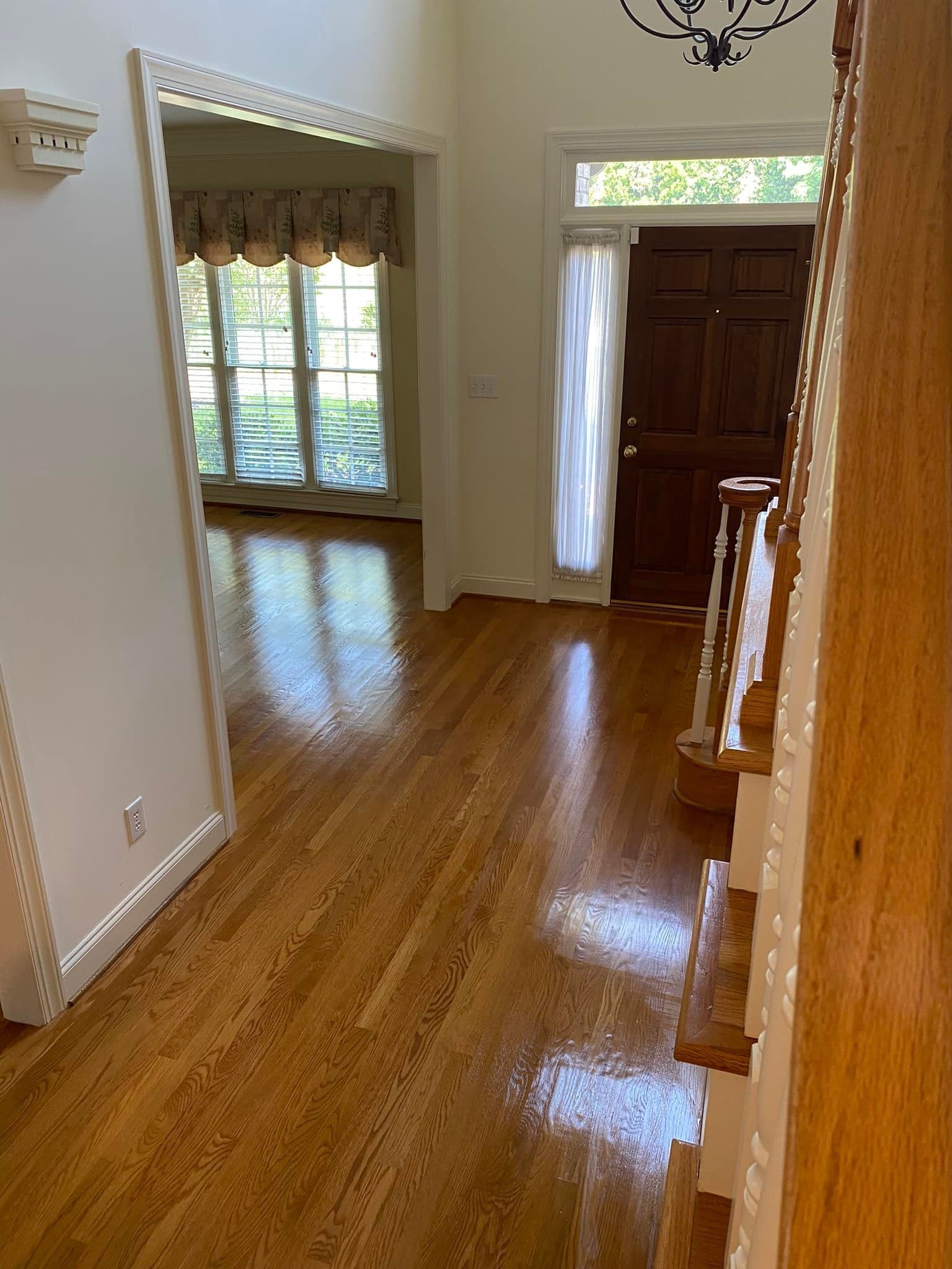 A hallway with hardwood floors and stairs in a house.