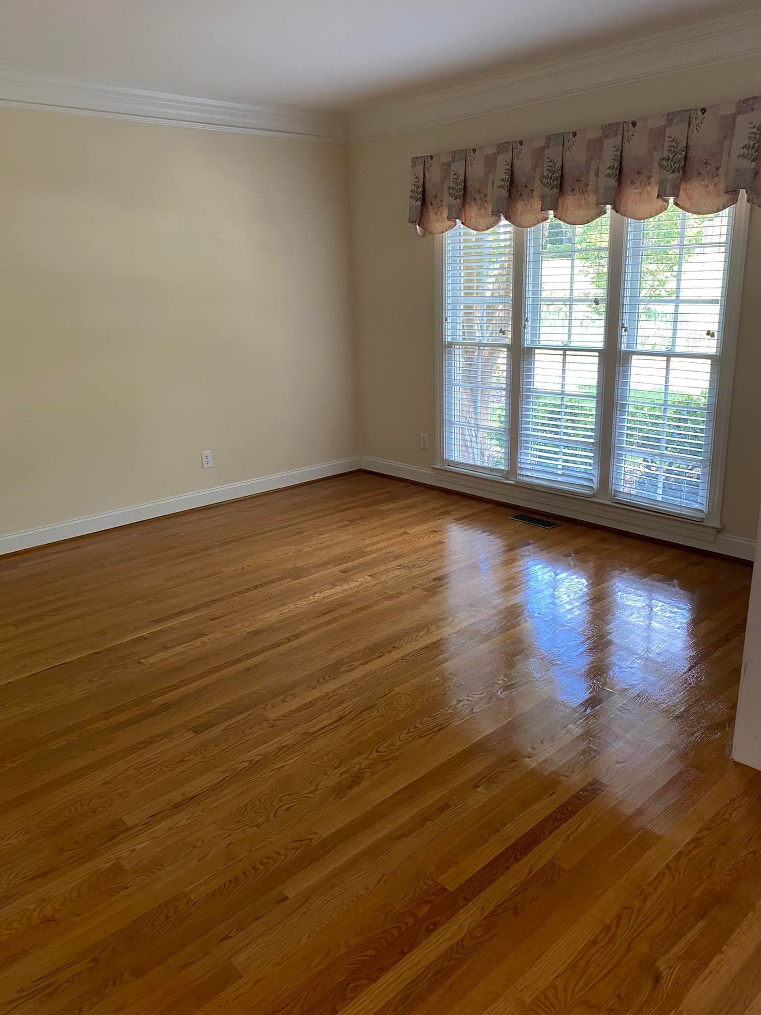 An empty living room with hardwood floors and sliding glass doors.