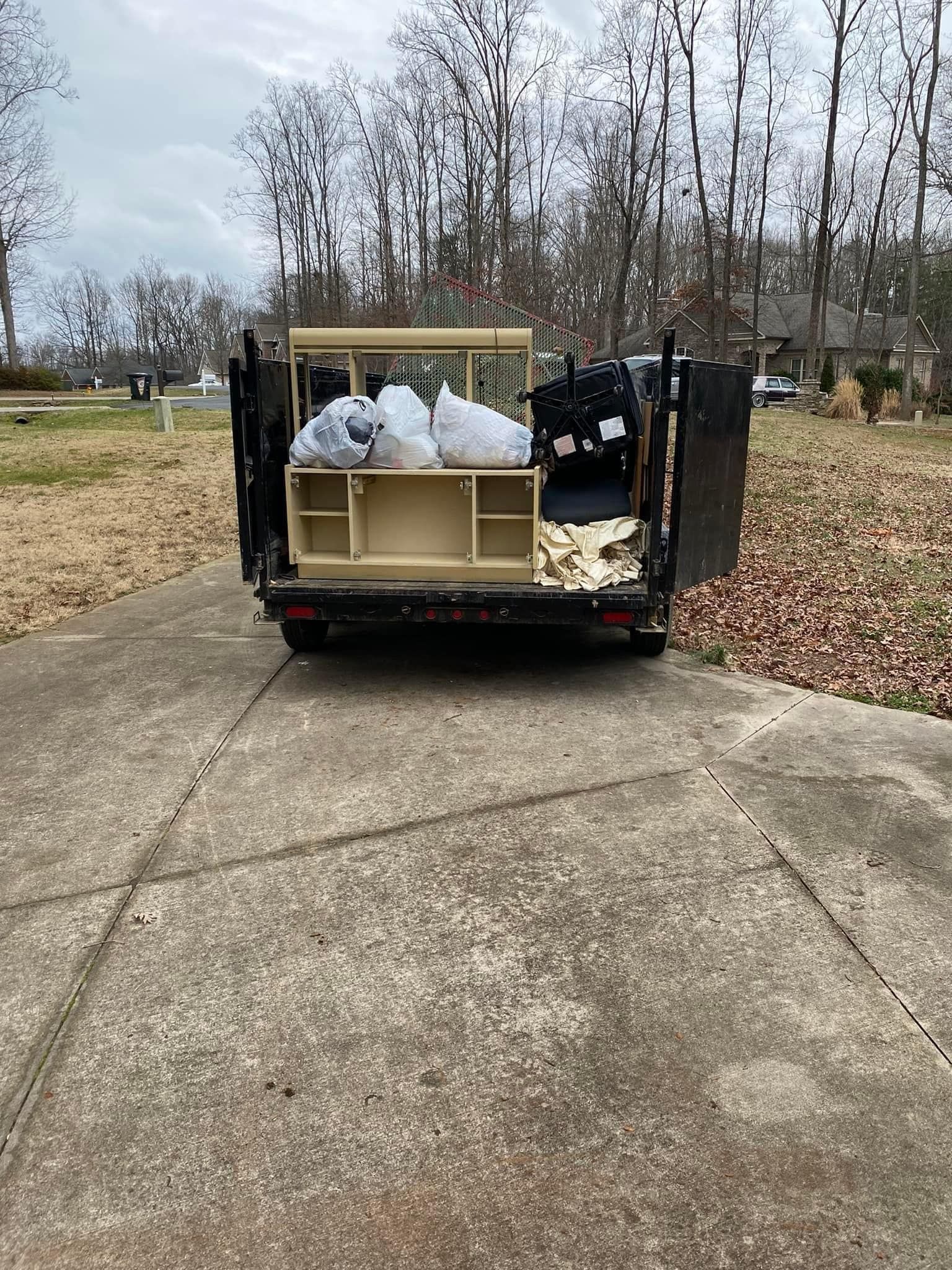 A dumpster filled with junk is parked on the side of the road.