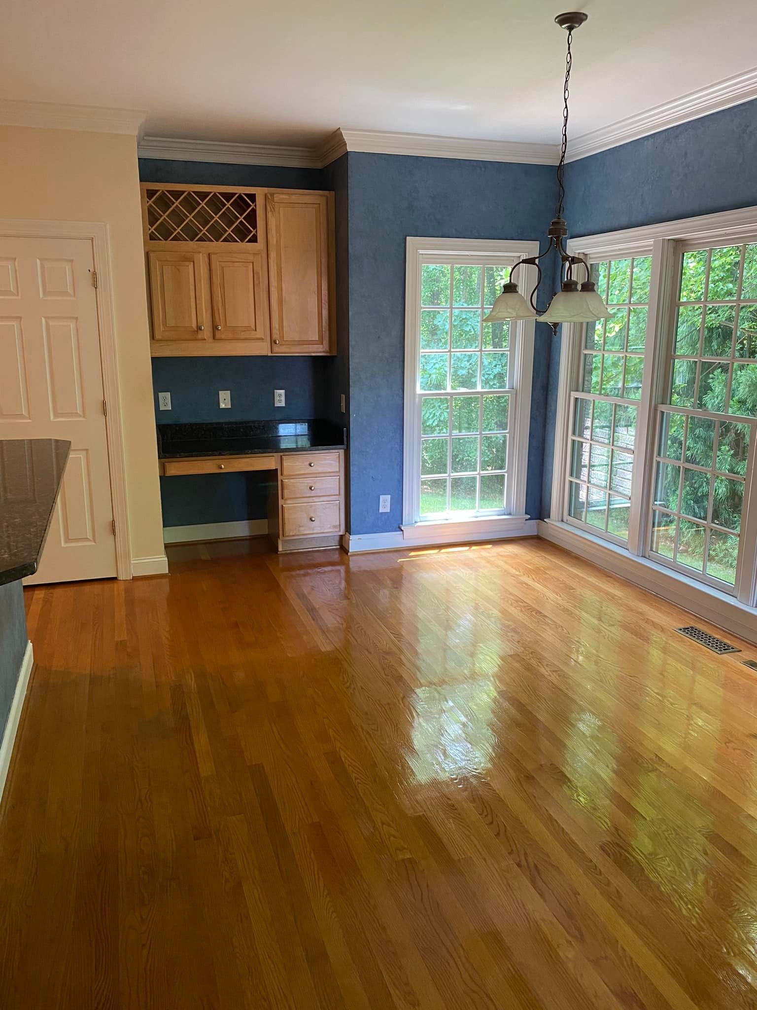 An empty living room with hardwood floors and blue walls.