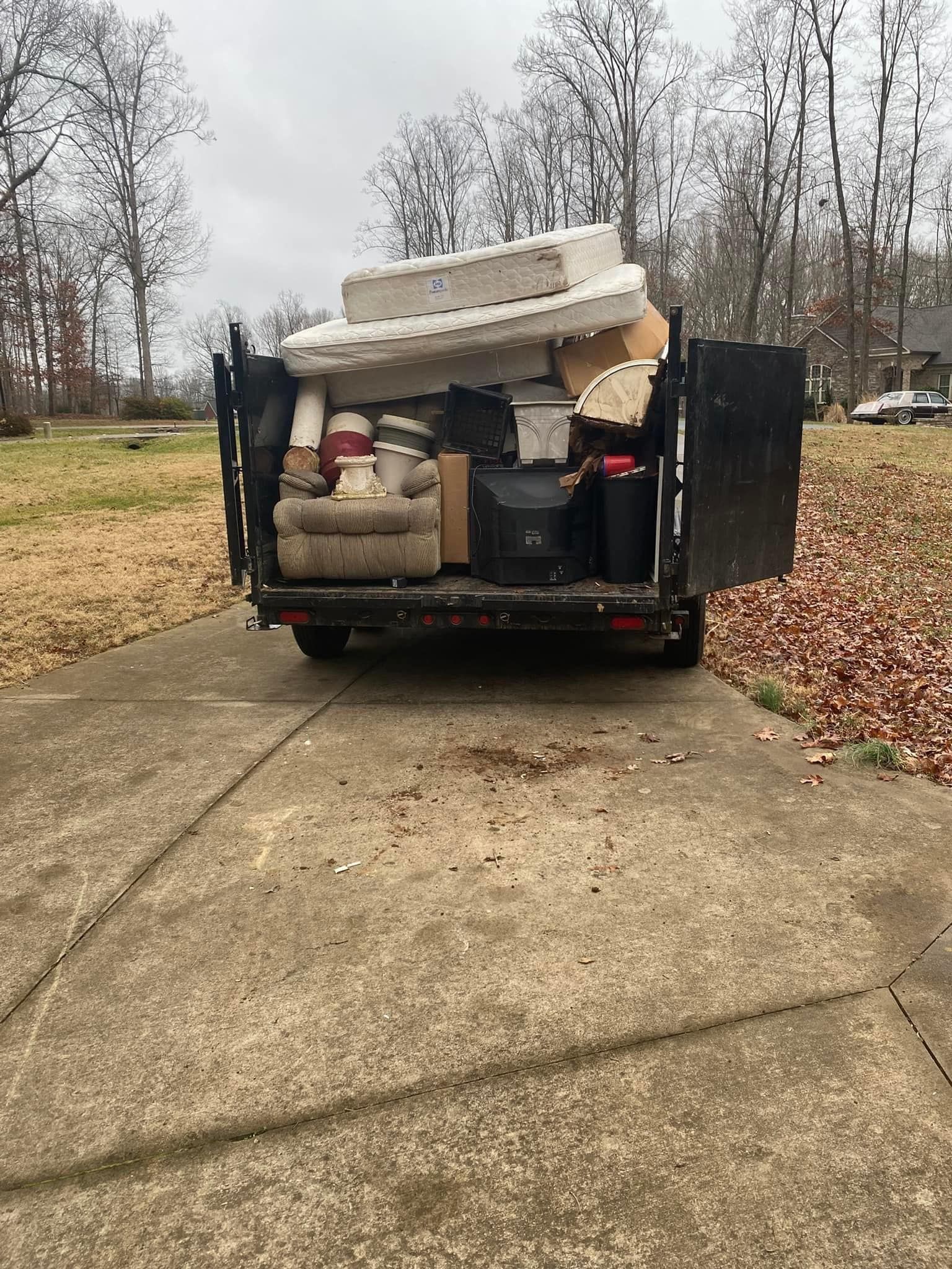 A dumpster filled with furniture is parked in a driveway.
