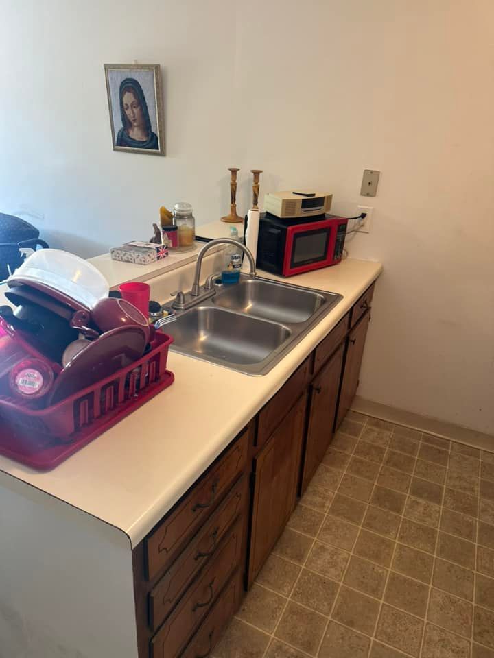 A kitchen with a sink a microwave and a picture on the wall