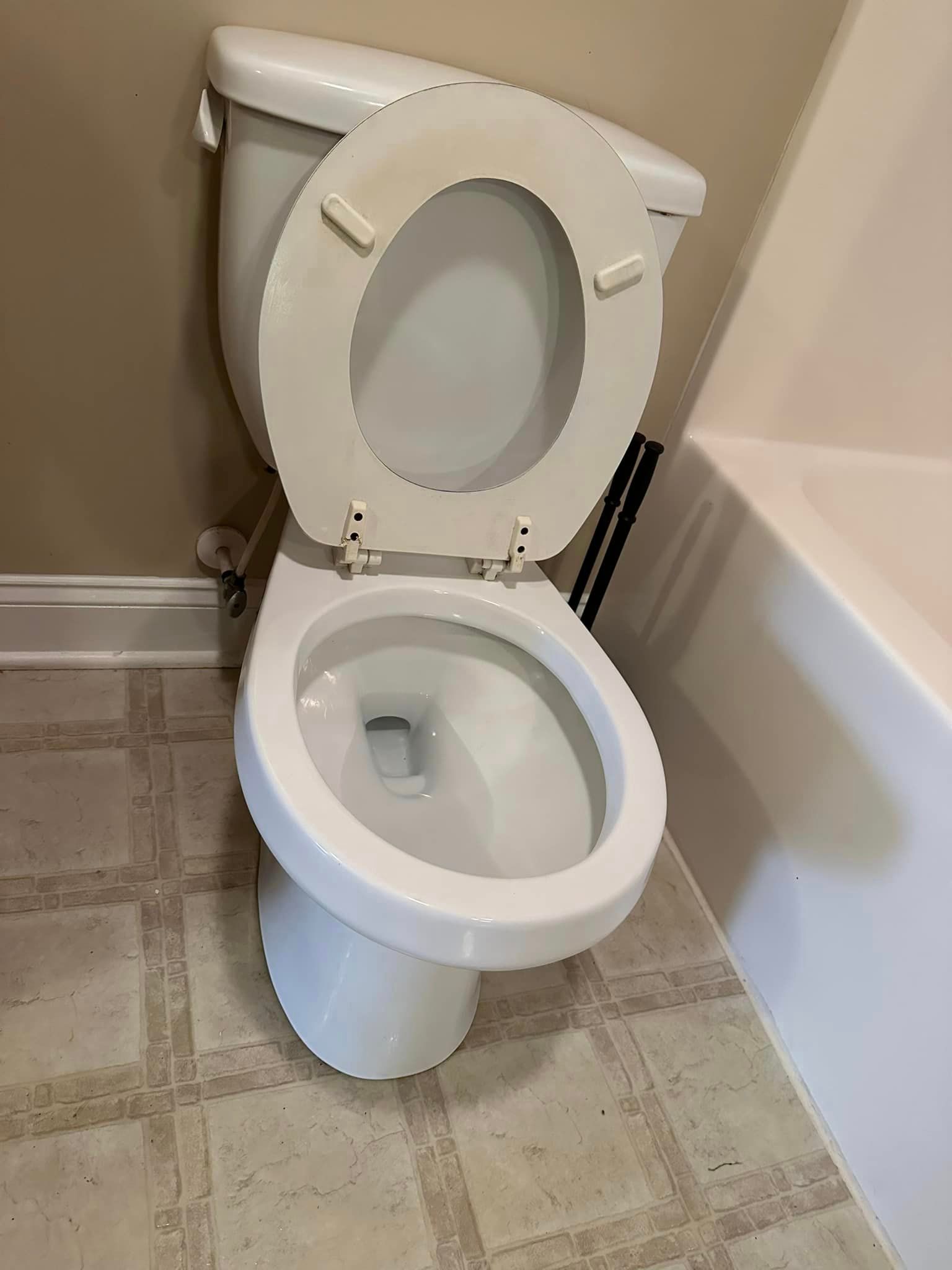 A white toilet is sitting in a bathroom next to a bathtub.