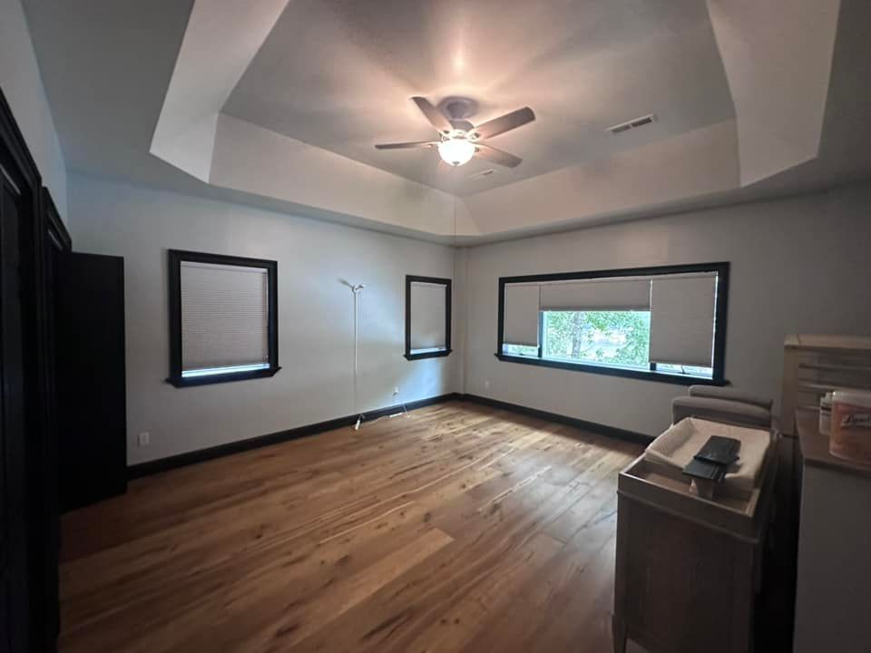 An empty room with hardwood floors and a ceiling fan