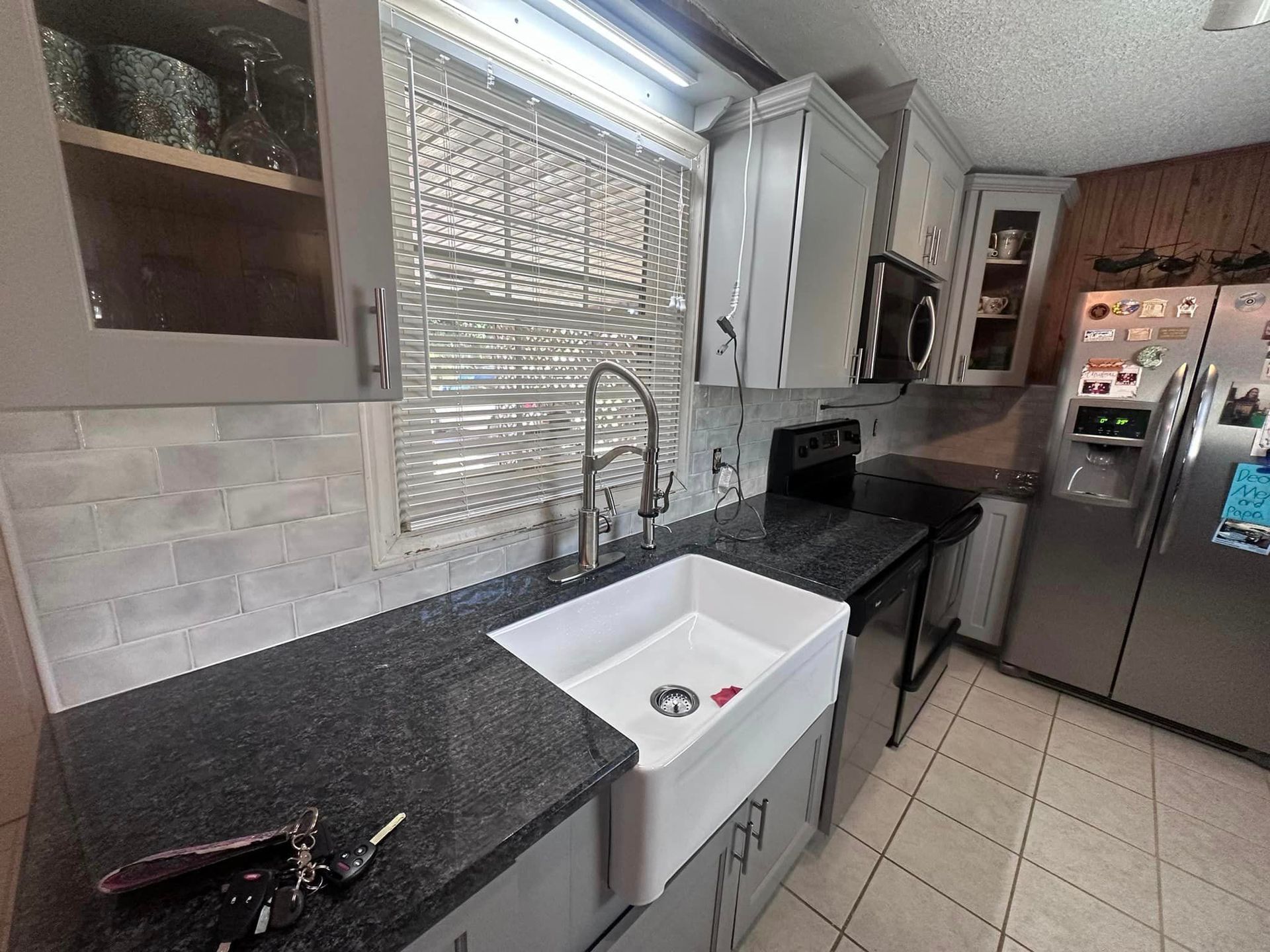 A kitchen with a white sink and black counter tops.