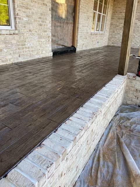A porch with a wooden floor and a white brick wall.