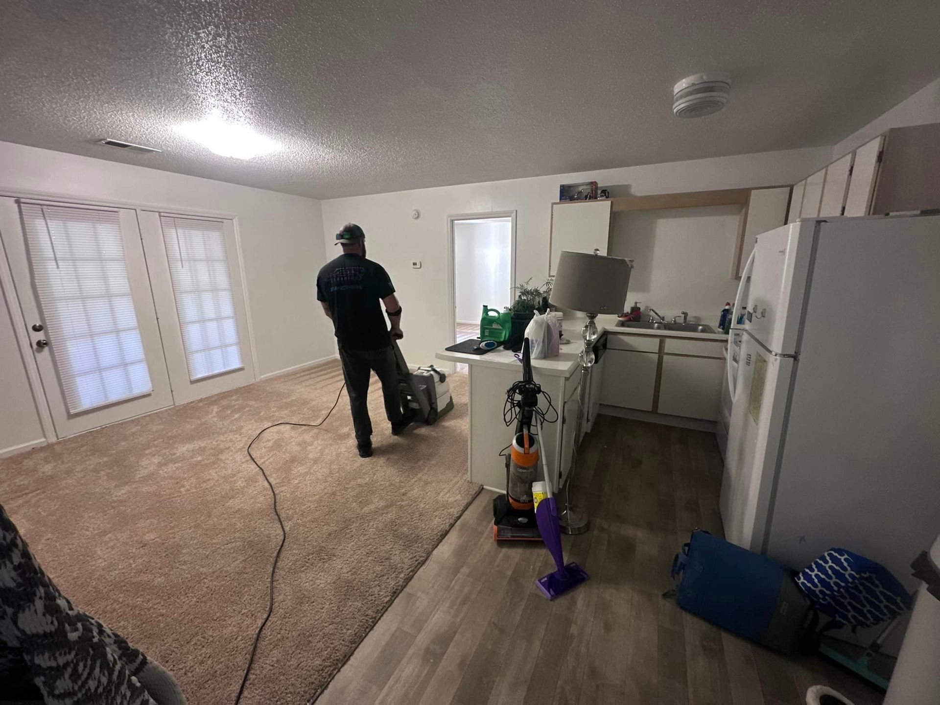 A man is standing in a living room with a vacuum cleaner.