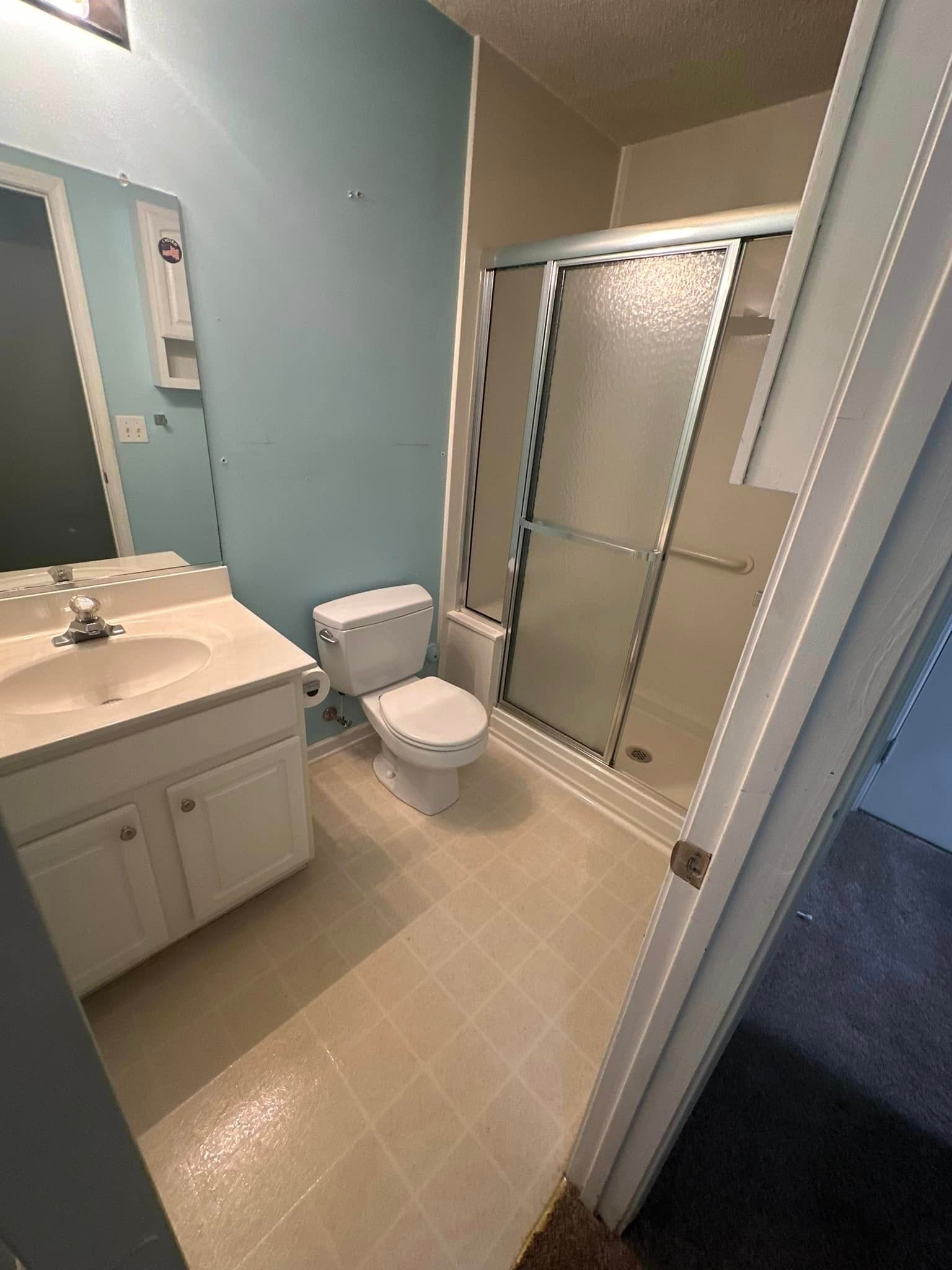 A bathroom with a toilet , sink and shower.