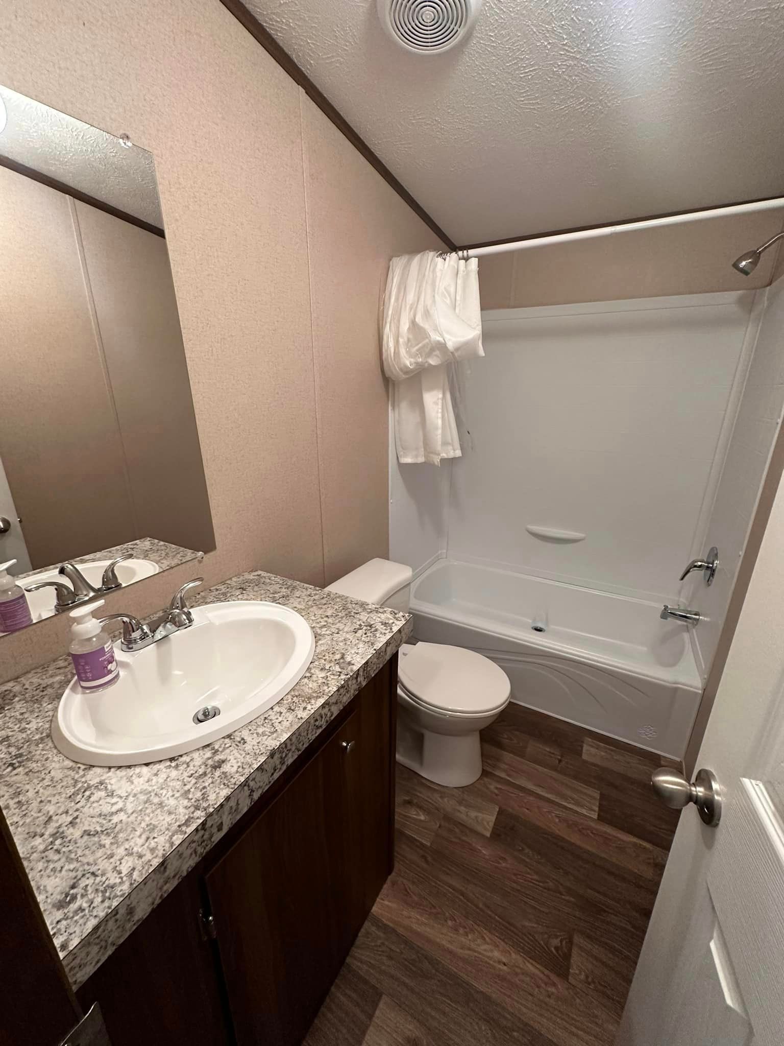 A bathroom with a sink , toilet , tub and mirror.