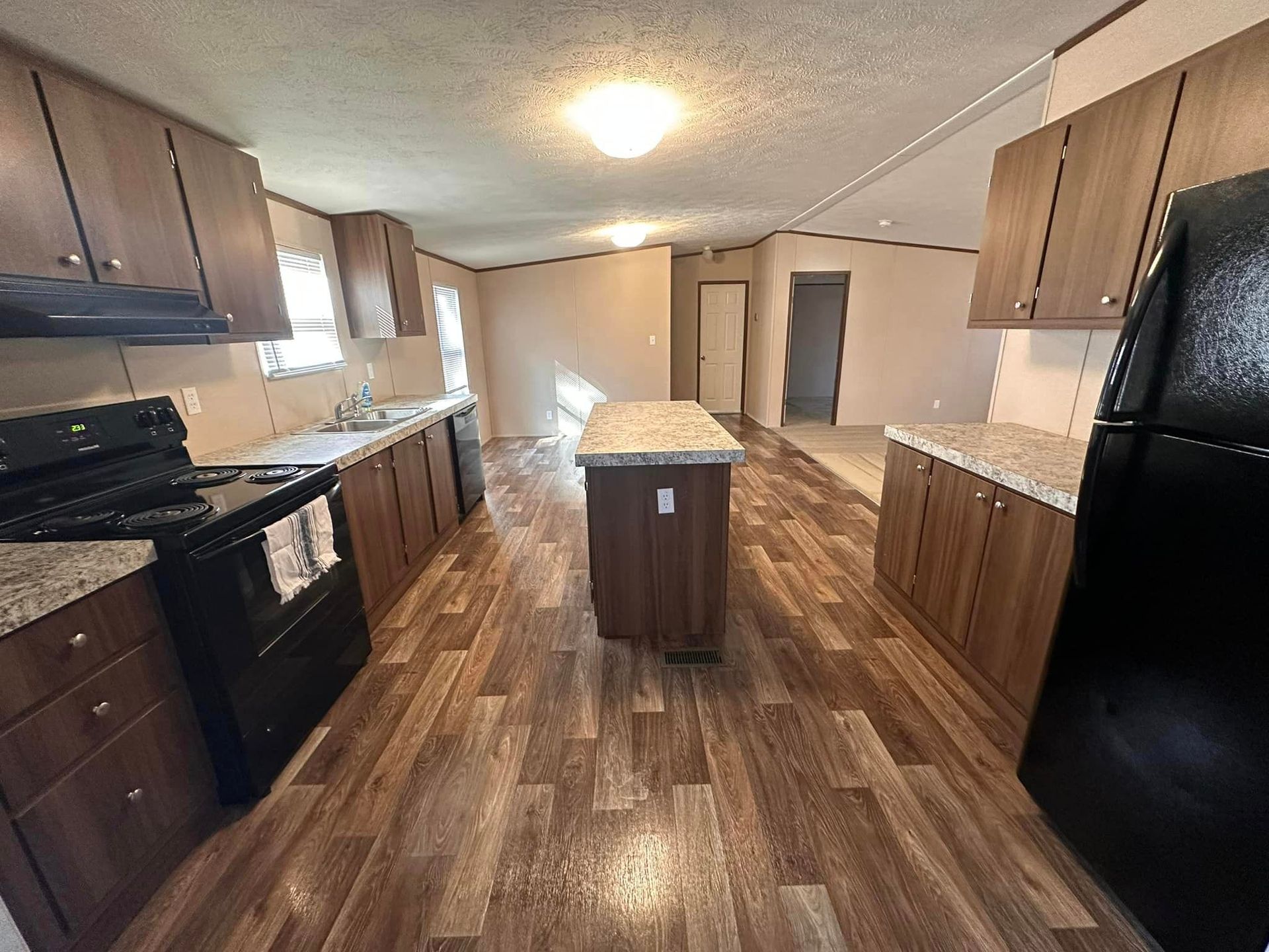 A kitchen in a mobile home with a stove , refrigerator , sink and cabinets.