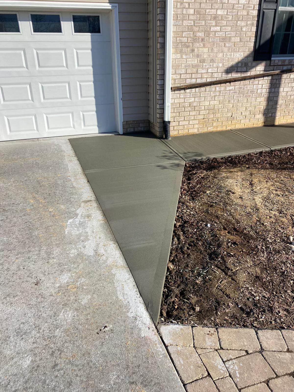 A concrete walkway is being built next to a garage door.