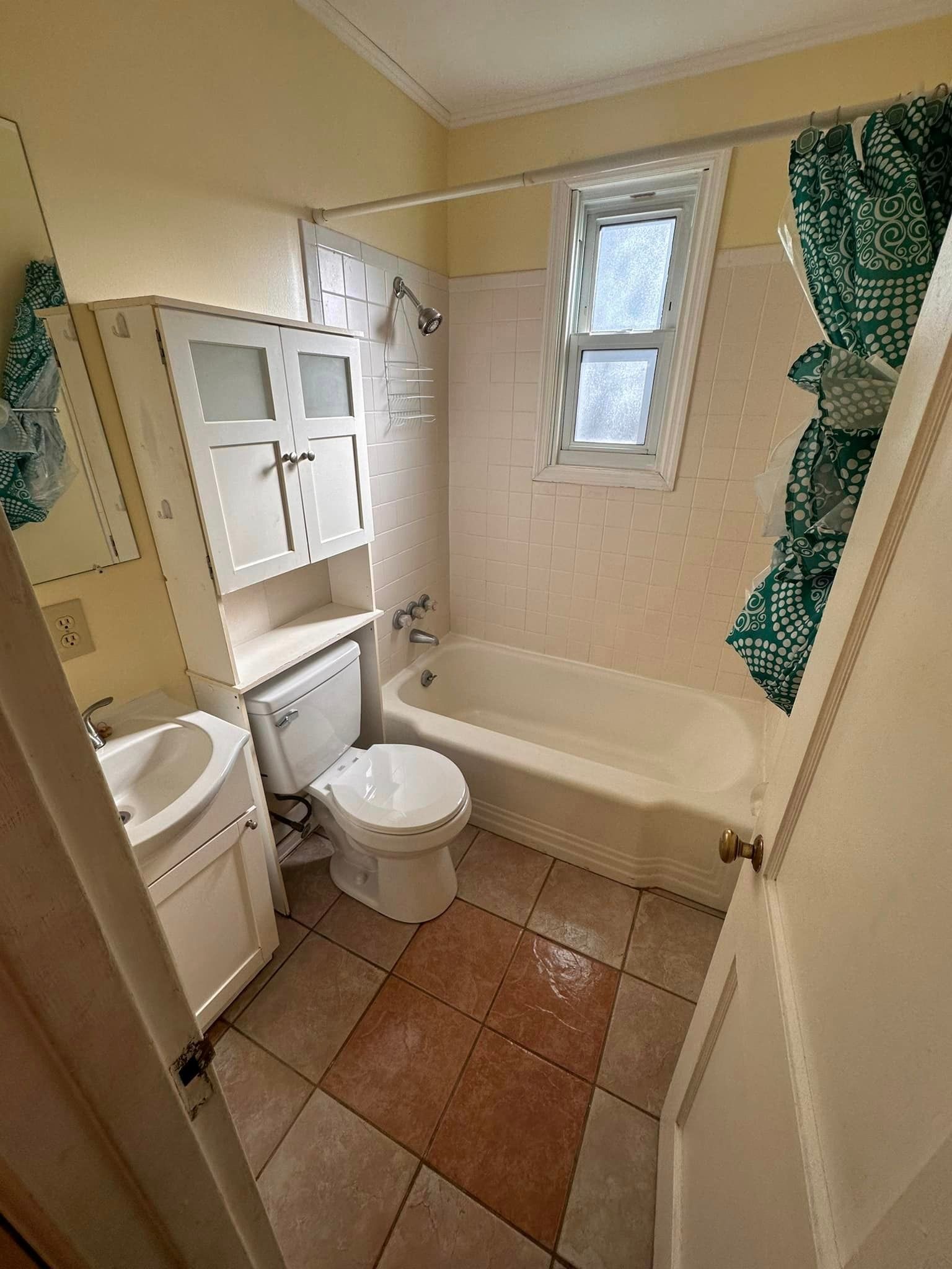 A bathroom with a toilet , sink , tub and window.