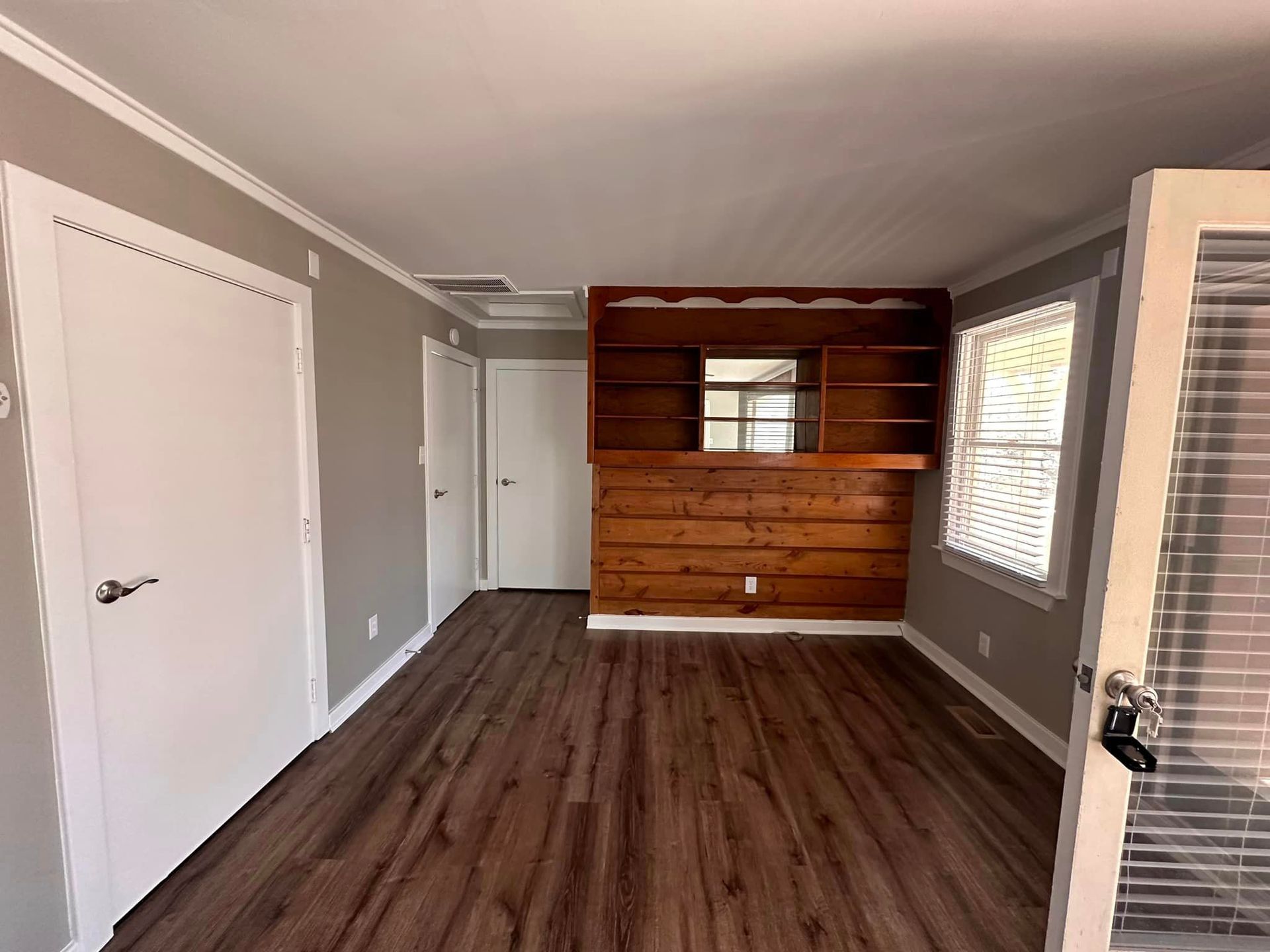 An empty living room with hardwood floors and a wooden wall.