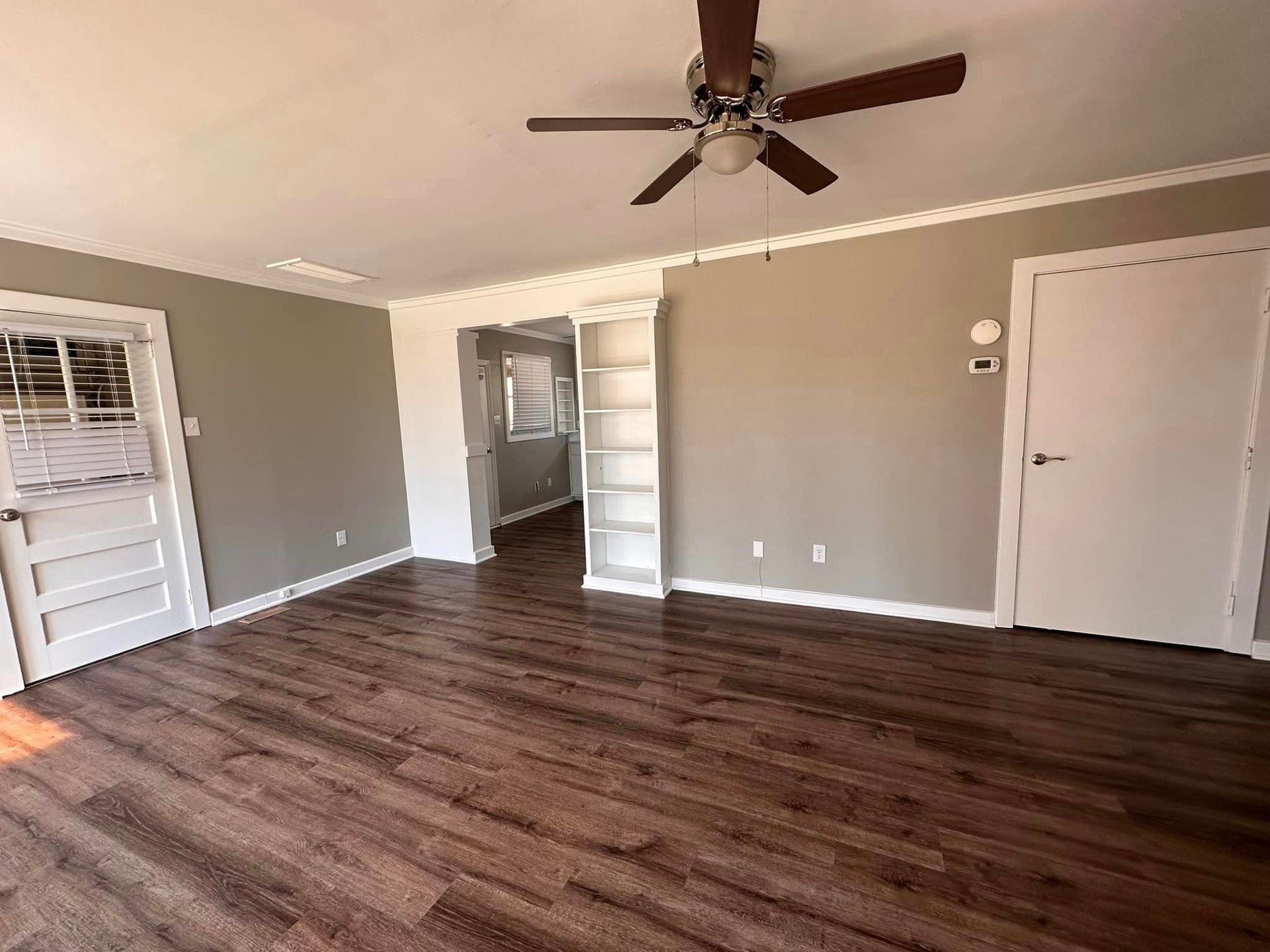 An empty living room with hardwood floors and a ceiling fan.