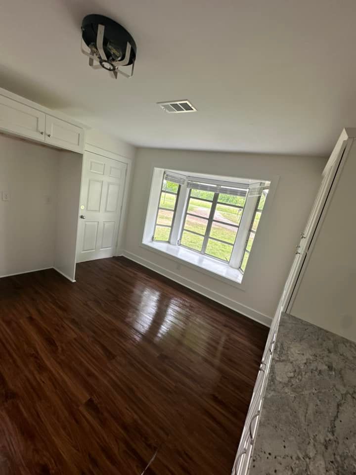 An empty room with hardwood floors and a large window.
