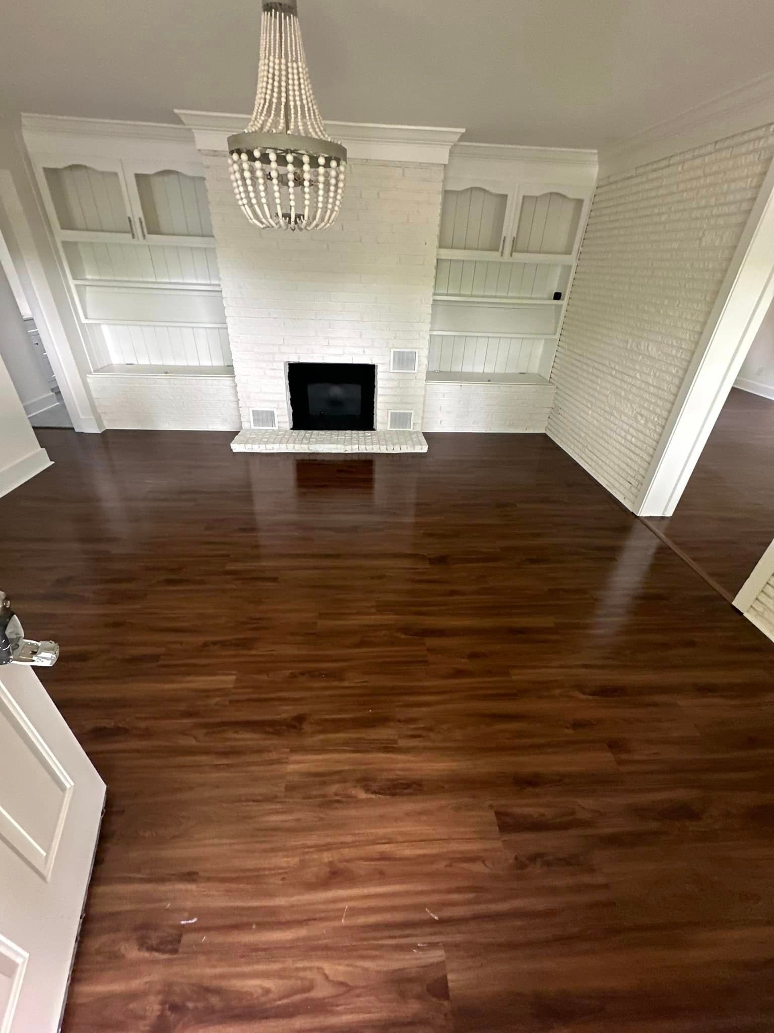An empty living room with hardwood floors and a fireplace.