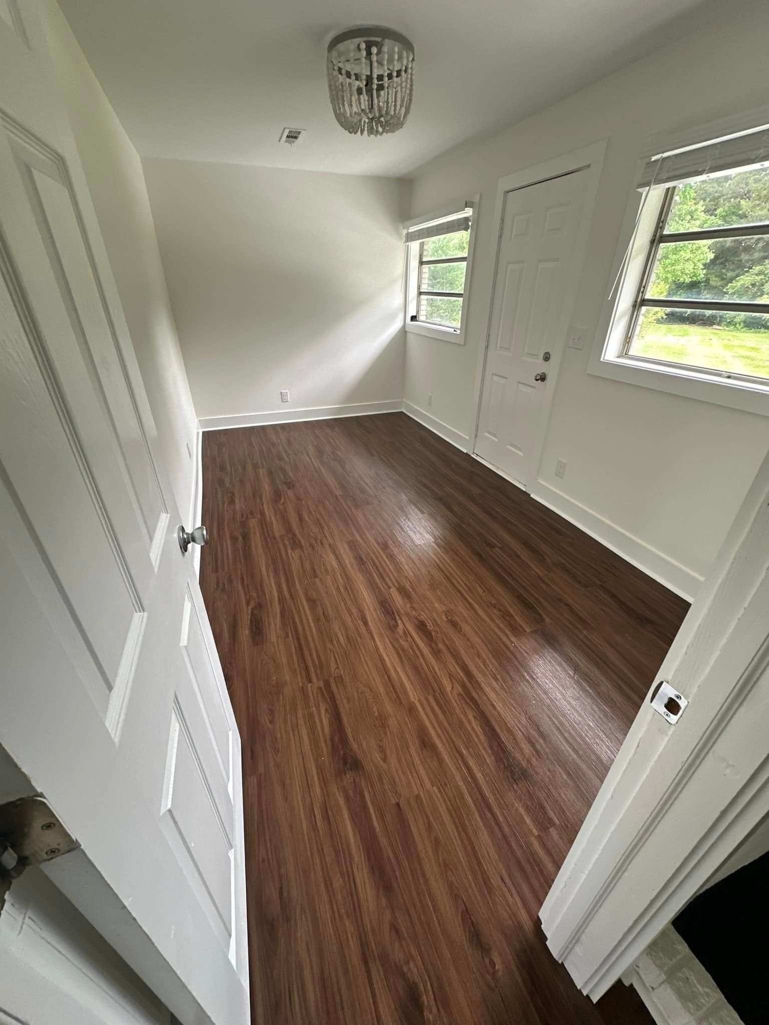 An empty room with hardwood floors and white walls.