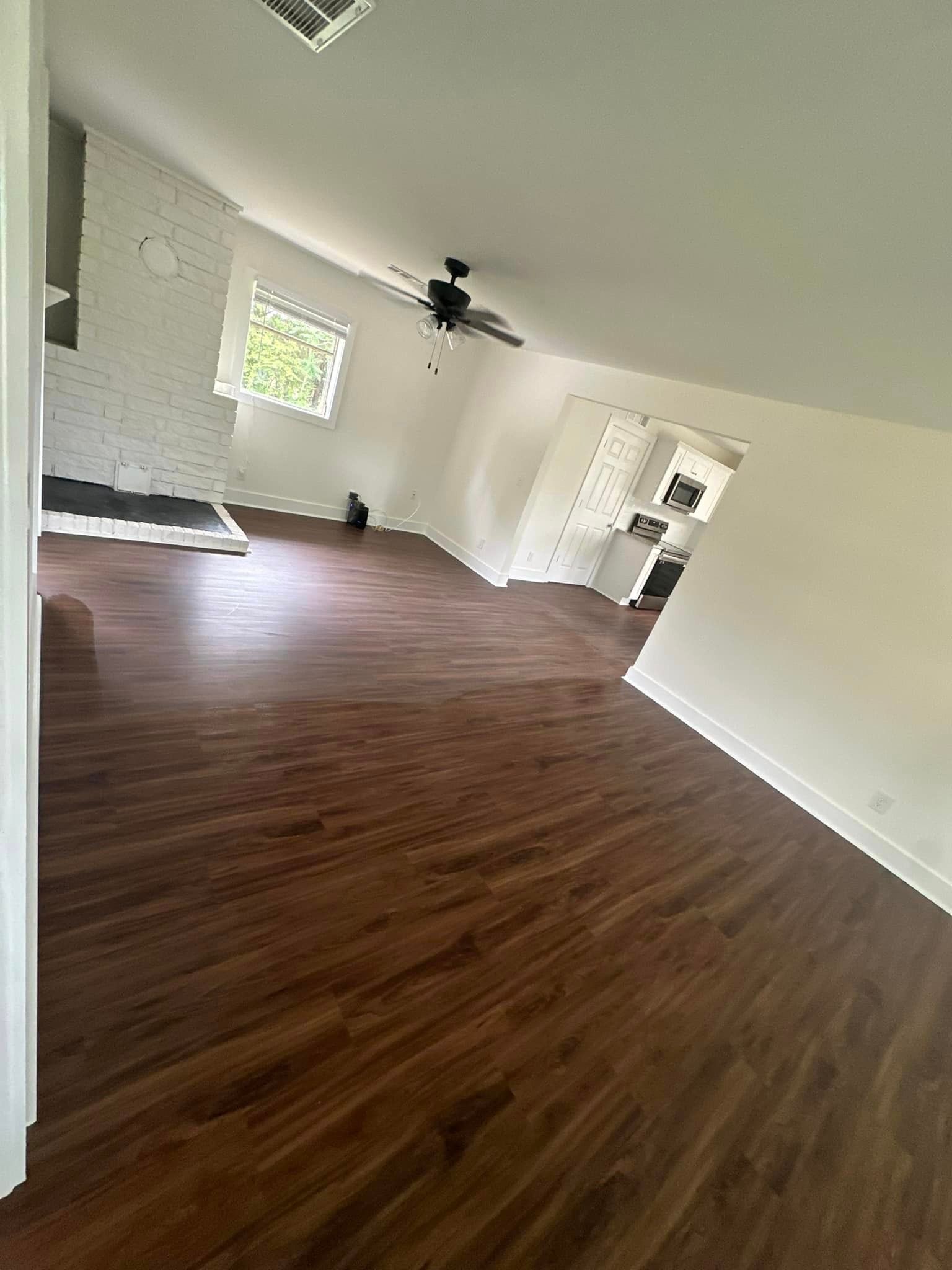 A living room with hardwood floors and a ceiling fan.