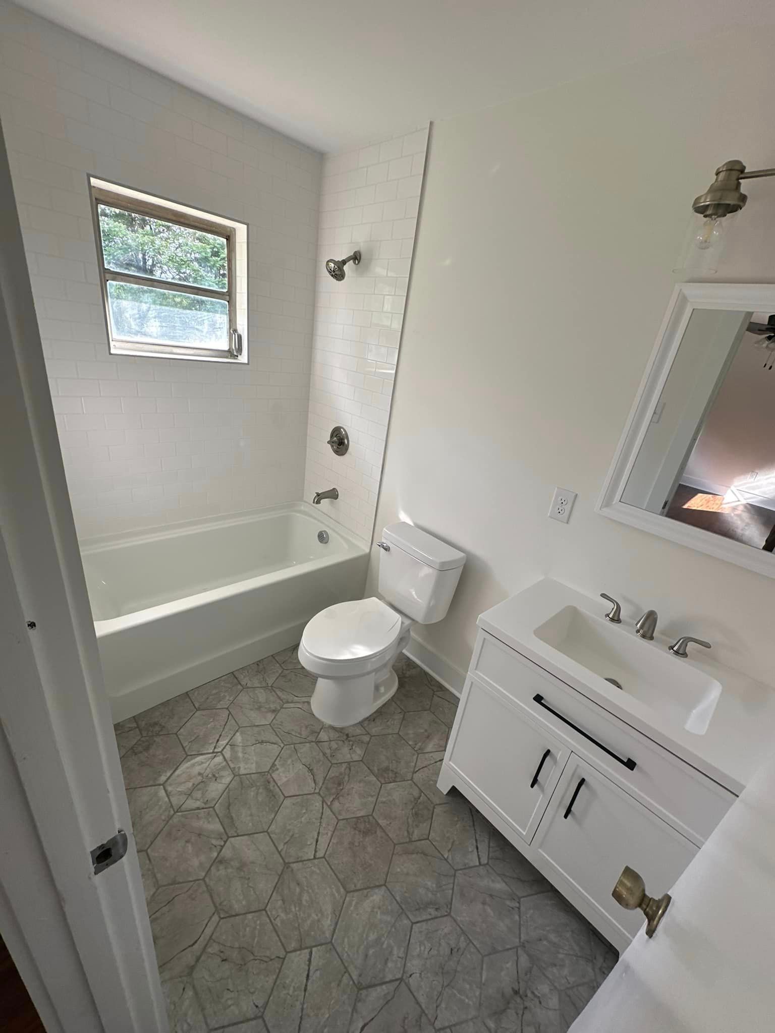 A bathroom with a toilet , sink , bathtub and mirror.