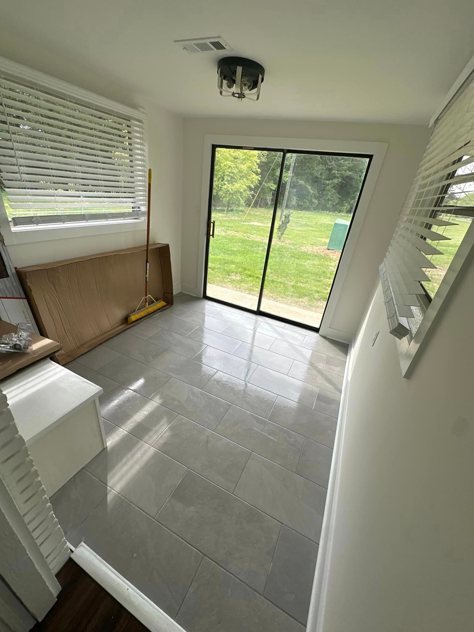 A room with a sliding glass door and a window with blinds.