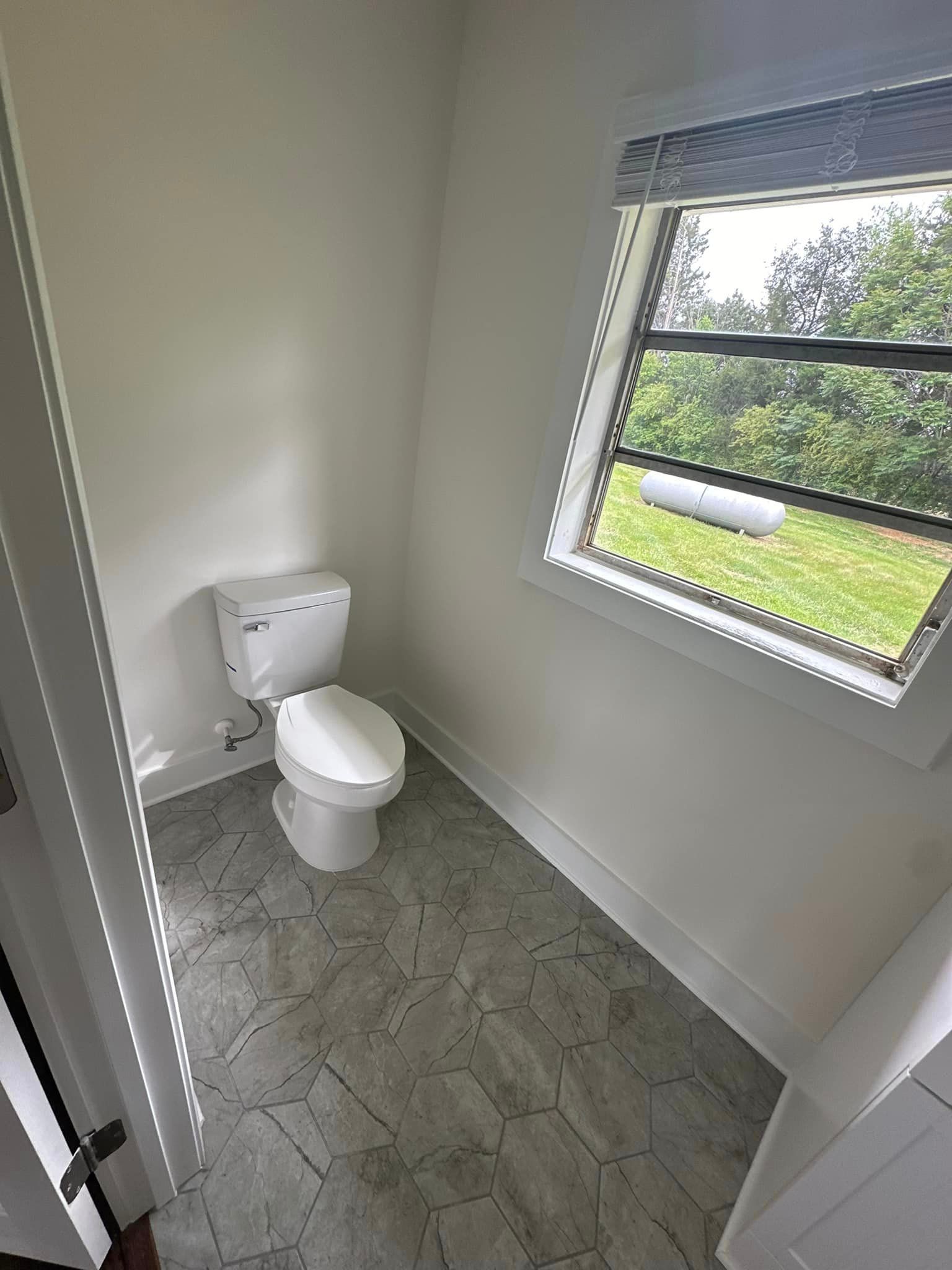 A bathroom with a toilet and a window.