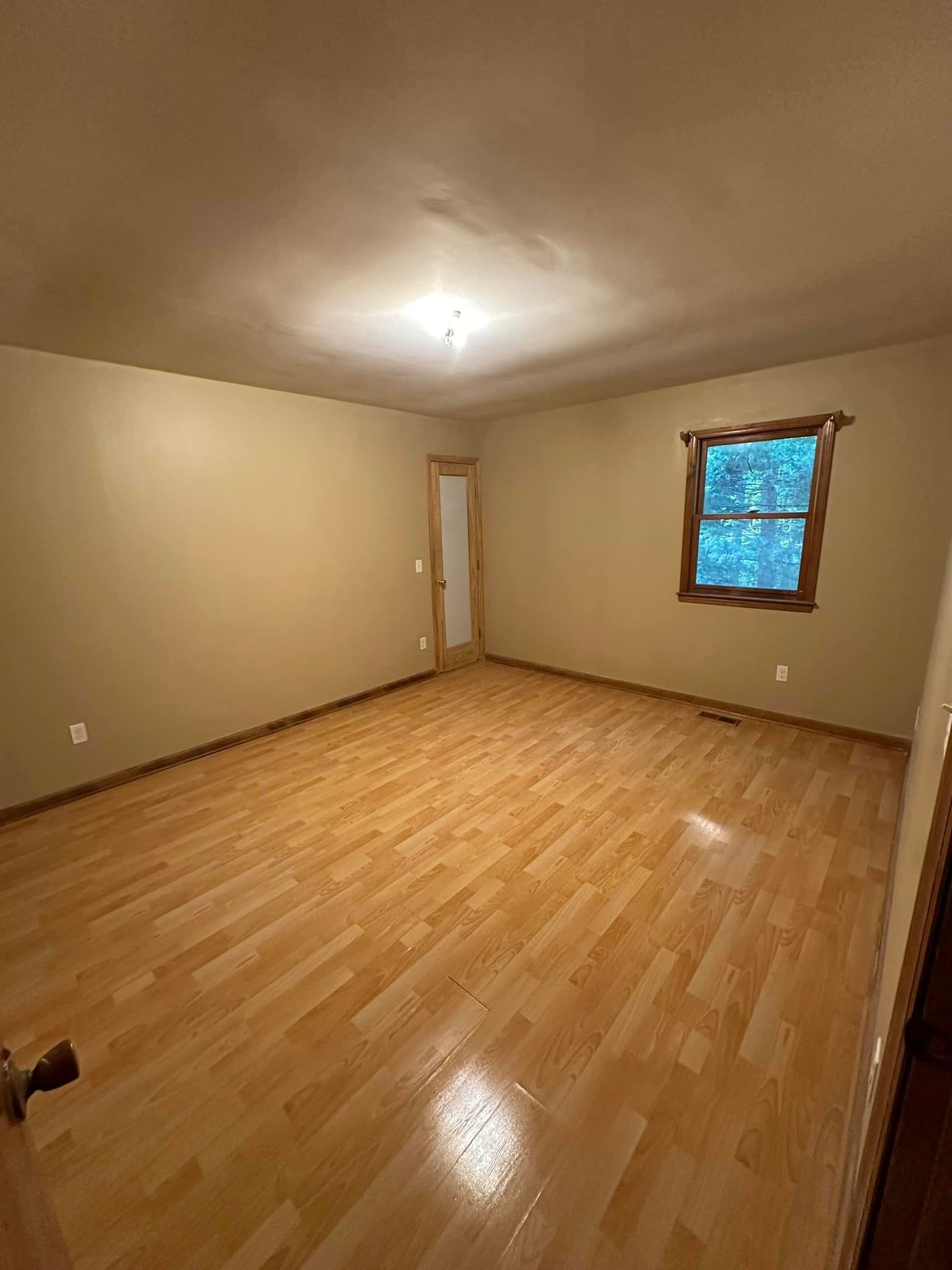 An empty room with hardwood floors and a window.