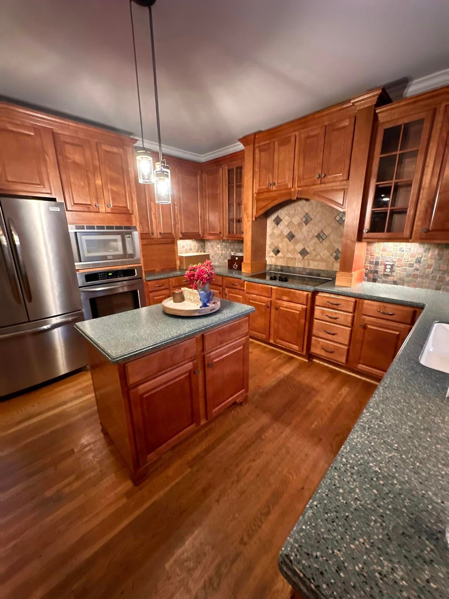 A kitchen with wooden cabinets , stainless steel appliances , and a large island.
