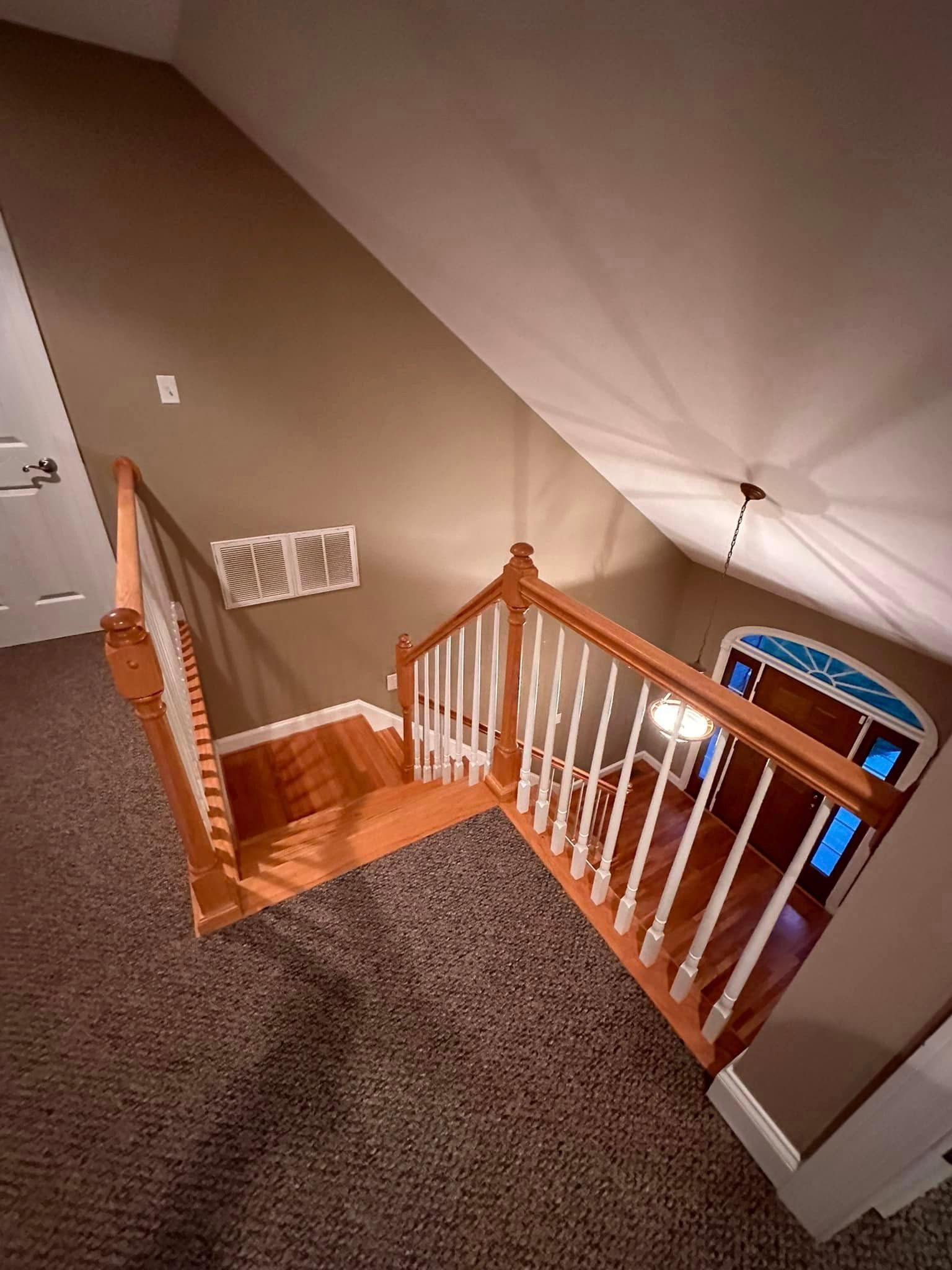 A wooden staircase with a white railing in a house.