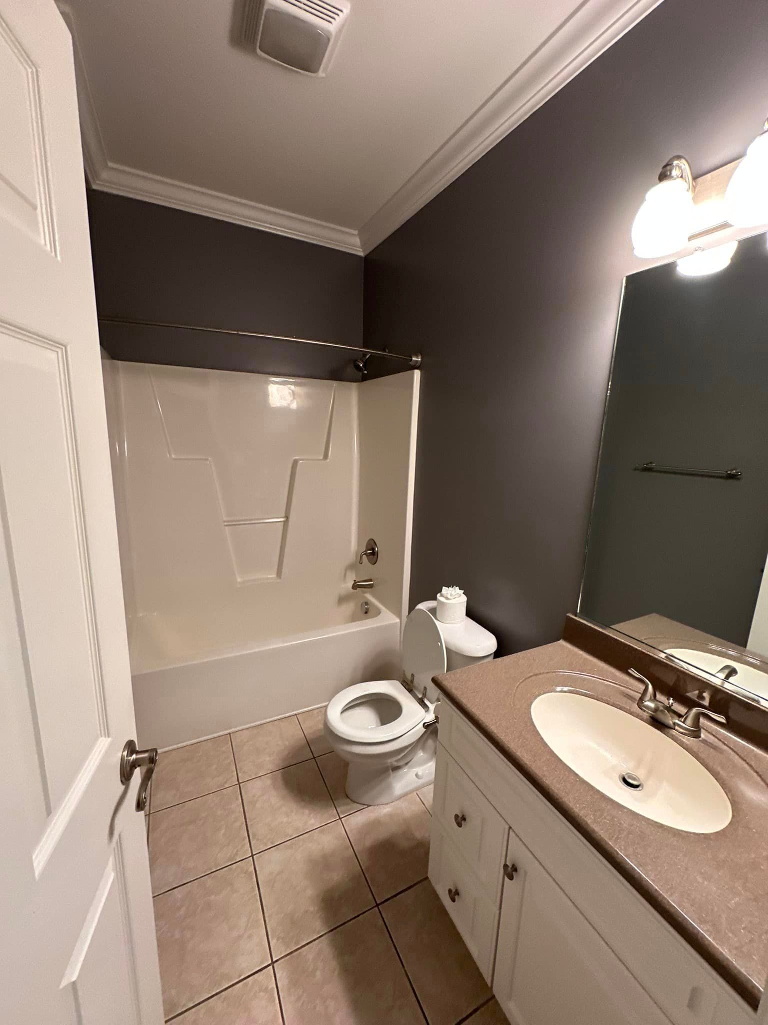 A bathroom with a toilet , sink , bathtub and mirror.