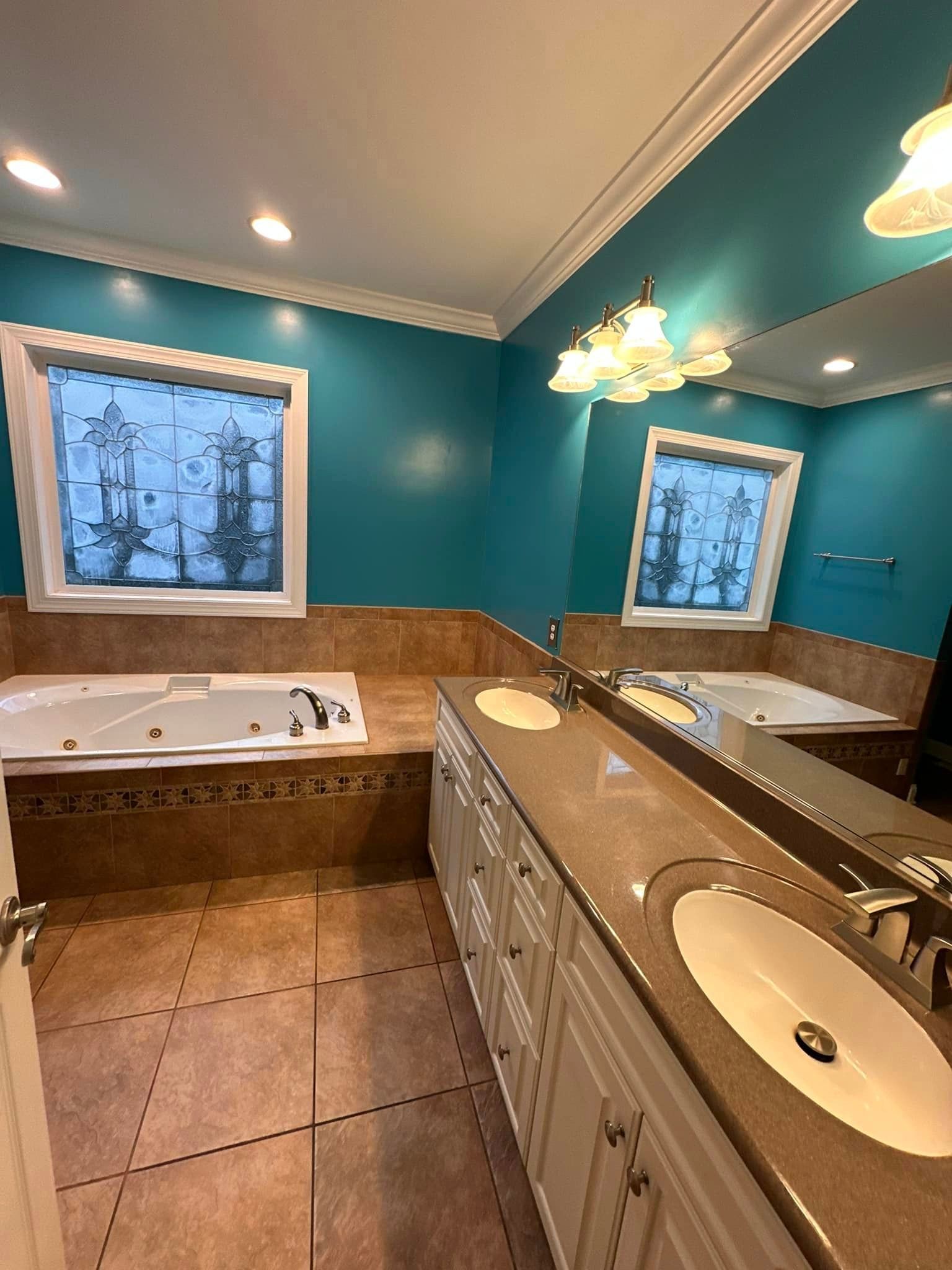 A bathroom with a jacuzzi tub , sink , and mirror.