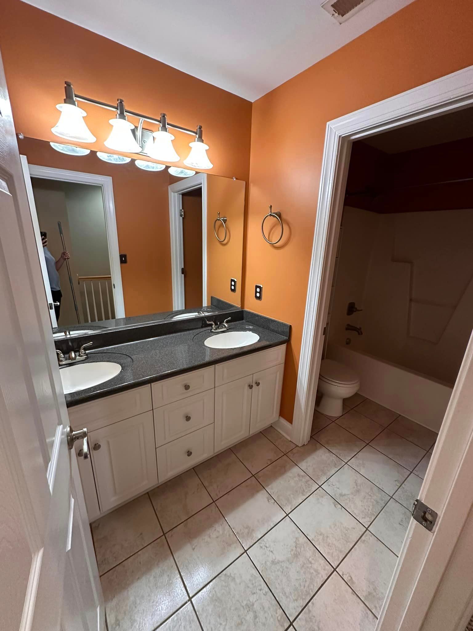 A bathroom with two sinks , a toilet , and a mirror.