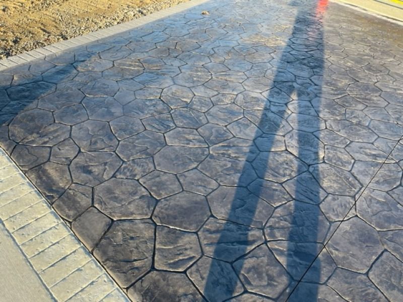 A shadow of a person is cast on a concrete driveway.