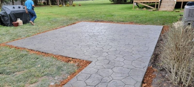 A concrete walkway is being built in the backyard of a house.