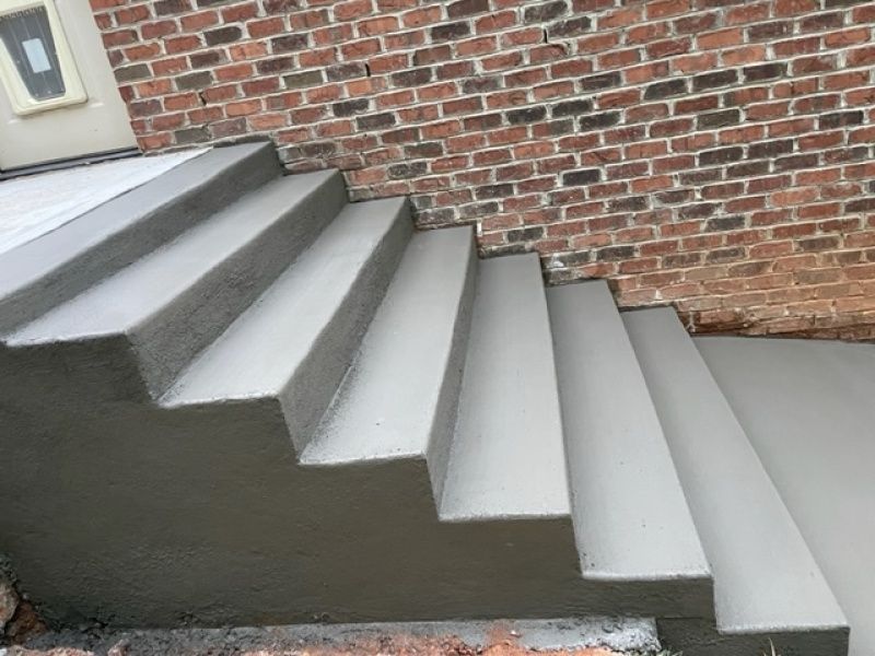 A set of concrete stairs leading up to a brick wall.