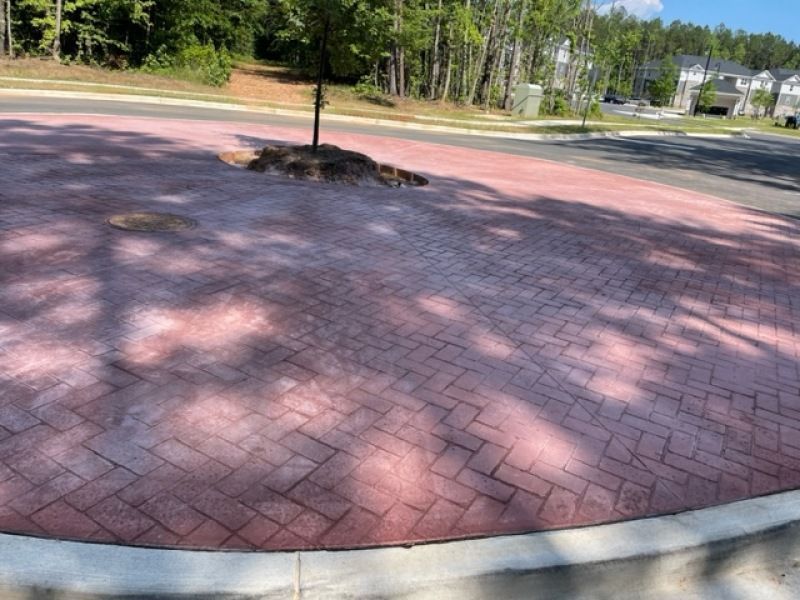 A red brick driveway with a tree in the middle of it.