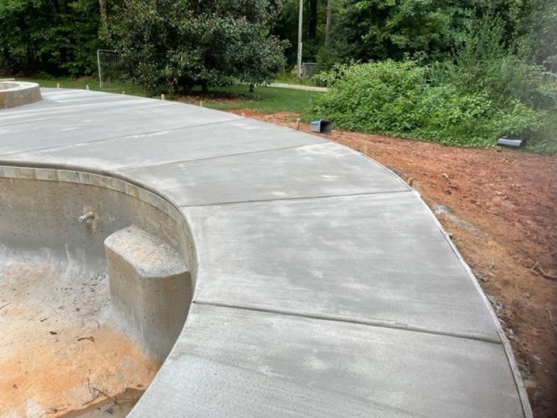 A concrete walkway is being built around a swimming pool.