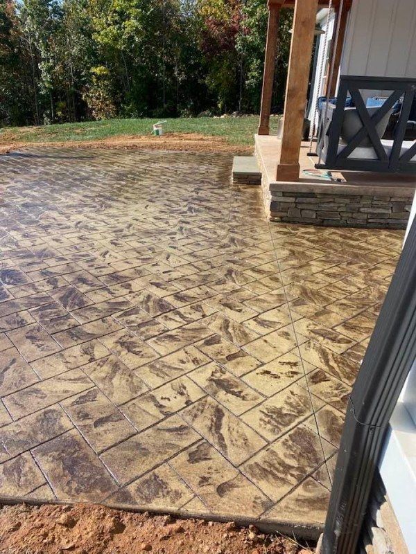 A concrete patio with a porch and a swing in the background.