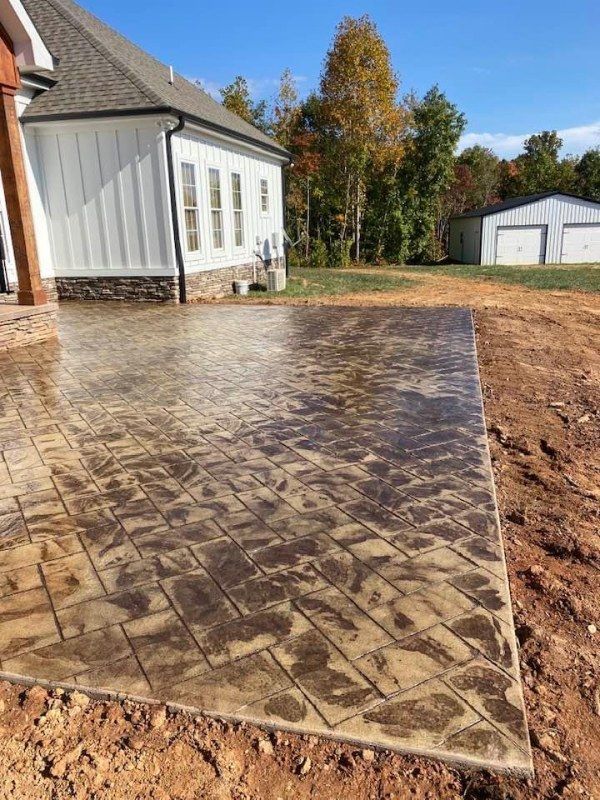 A concrete patio in front of a house with a garage in the background.