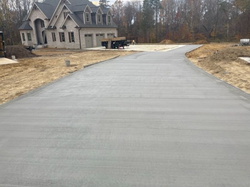 A concrete driveway leading to a large house.