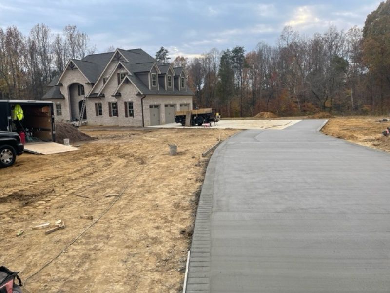 A large house is being built next to a concrete driveway.