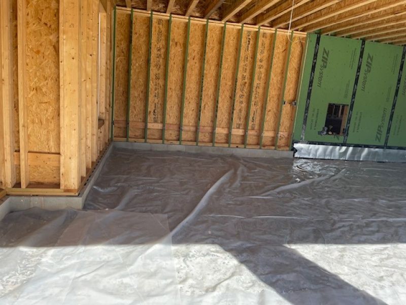 A room in a house under construction with a plastic sheet on the floor.