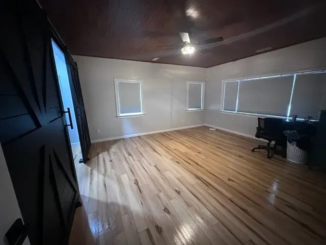 A large room with hardwood floors and a ceiling fan.