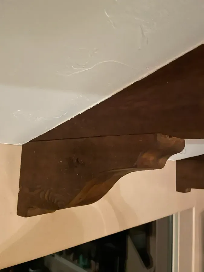 A wooden beam is hanging from the ceiling above a window.