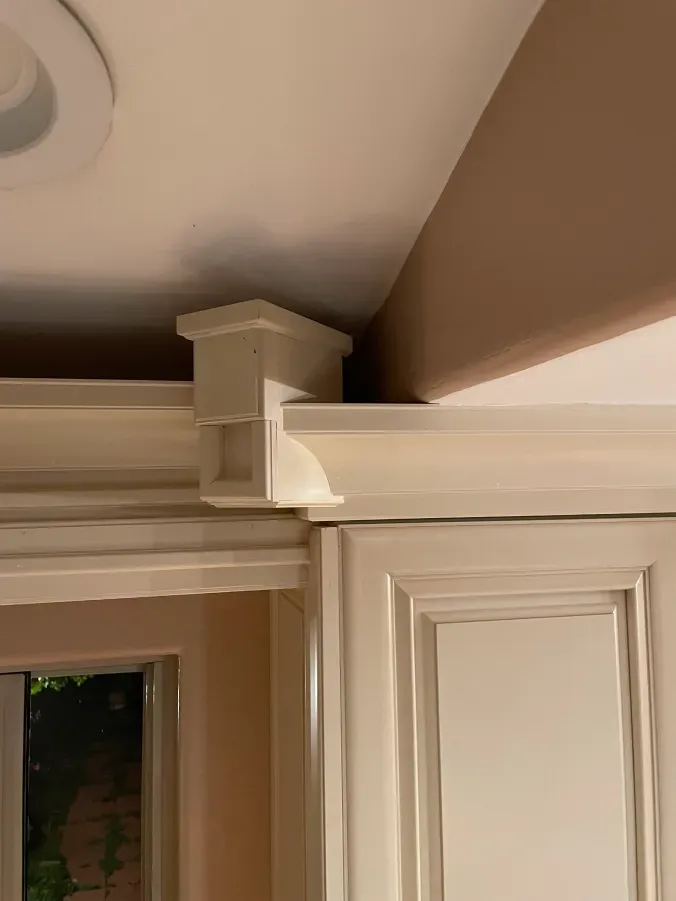 A kitchen with white cabinets and a brown ceiling.